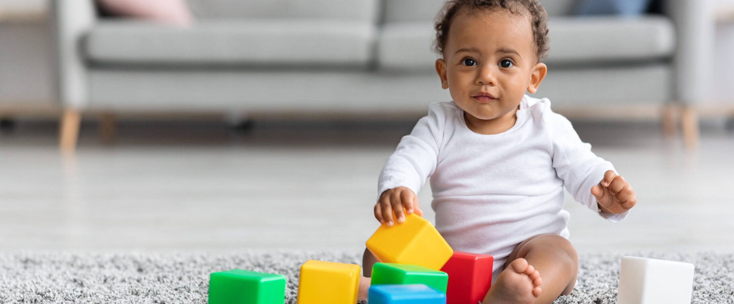 Adorable Black Infant Baby Playing With Stacking Building Blocks At Home Baby with Toys on Floor